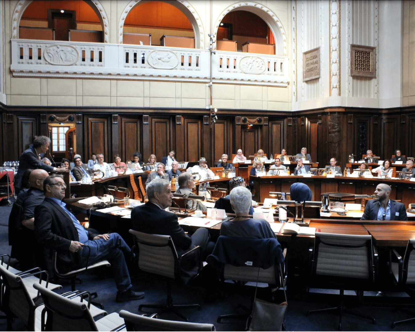 Ein Saal mit einem runden Tisch um den Vertreter*innen verschiedener Räte der Religionen zum Bundeskongress der Räte der Religionen zusammensitzen.