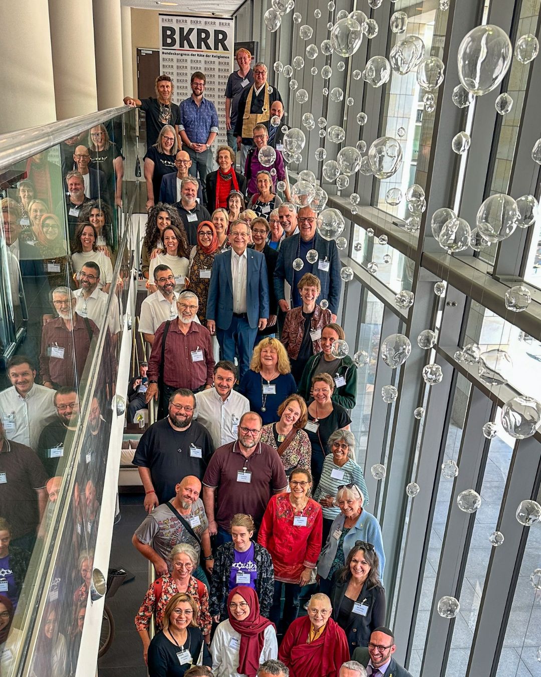 Gruppenbild der Teilnehmenden des 7. Bundeskongress der Räte der Religionen in Dresden. Auf einer Treppe stehenden. Im Hintergrund ein Banner mit dem Logo.